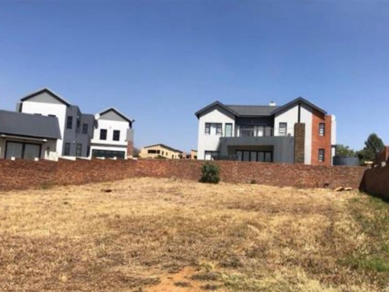 A vacant residential plot of land enclosed by brick boundary walls, situated in a developed estate with surrounding modern residential properties.