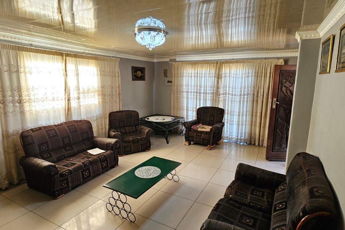 A spacious living room featuring tiled flooring, decorative crown molding, and a high-gloss reflective ceiling finish.