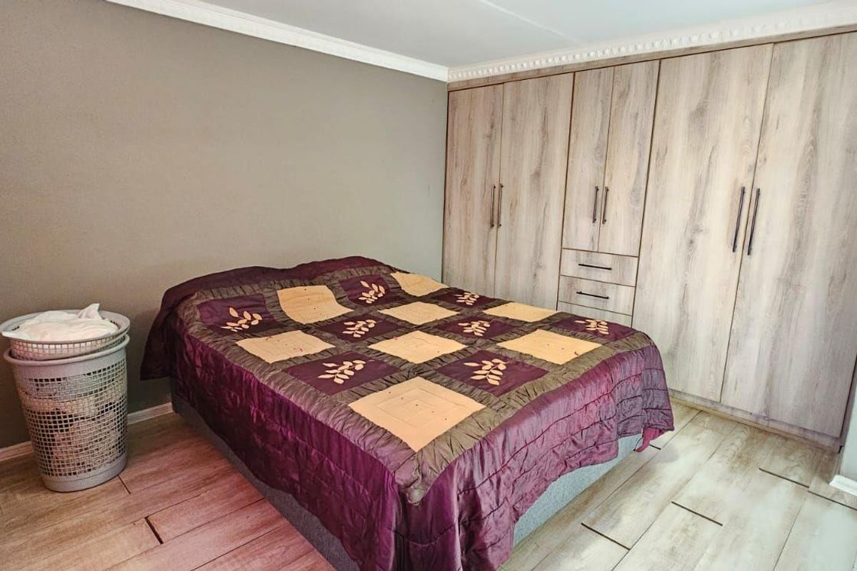 A bedroom featuring wood-look tile flooring and extensive built-in cabinetry with a light wood finish.