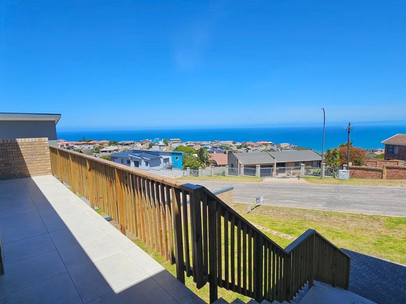 Elevated balcony featuring a wooden balustrade with expansive coastal and neighbourhood views.