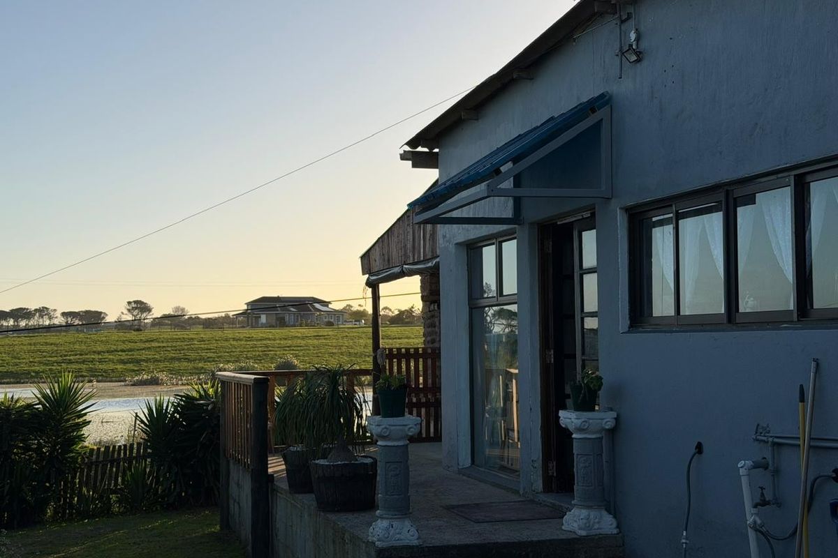 Rear exterior view of the property featuring a timber deck, sliding door access, and an awning, overlooking a rural landscape.