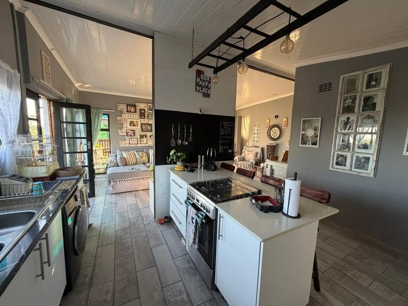 Open-plan kitchen and living area featuring a central island with gas hob, stone countertops, and modern timber-look floor tiles throughout.