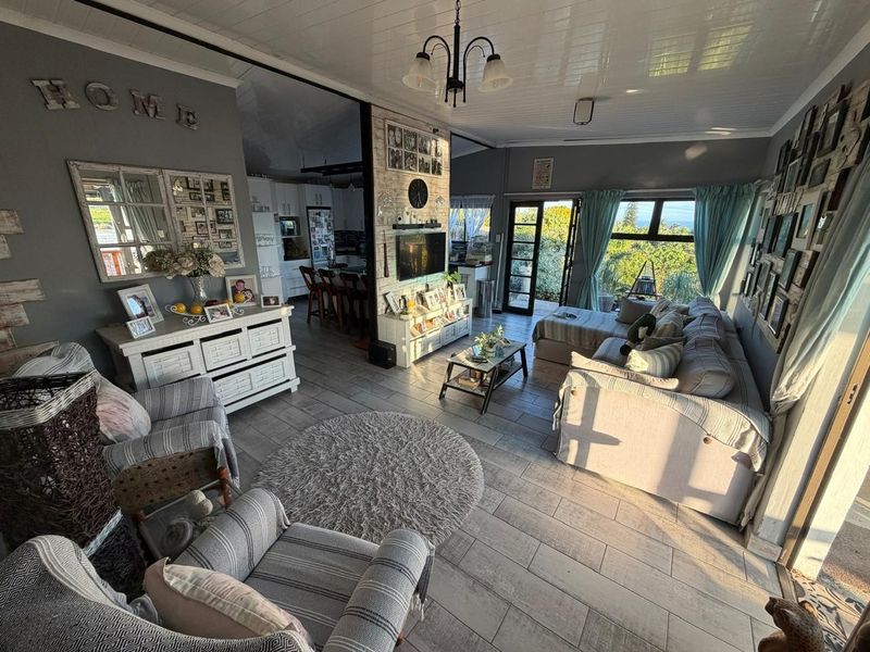 Spacious open-plan living area featuring tiled floors, a tongue and groove ceiling, and seamless flow to the kitchen and outdoor patio area.