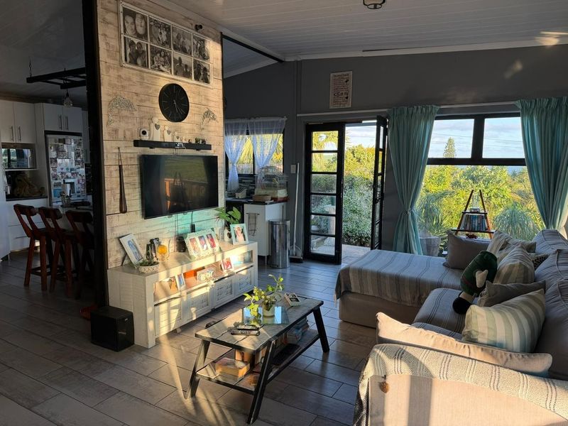 Open-plan living area featuring tiled floors, a timber-look feature wall, and direct access to the garden through glass-paned french doors.