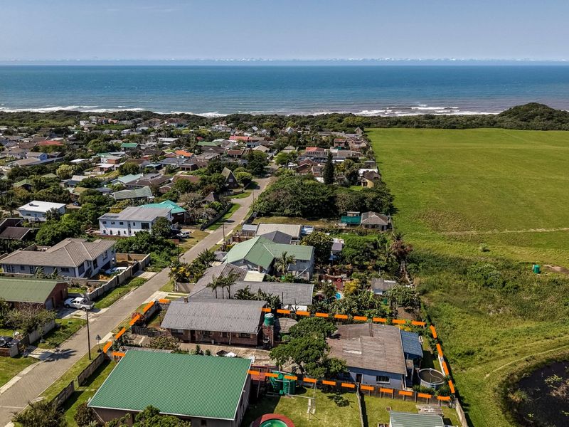 Aerial view of the property highlighting its location near the coastline, adjacent to open green space and a small pond.