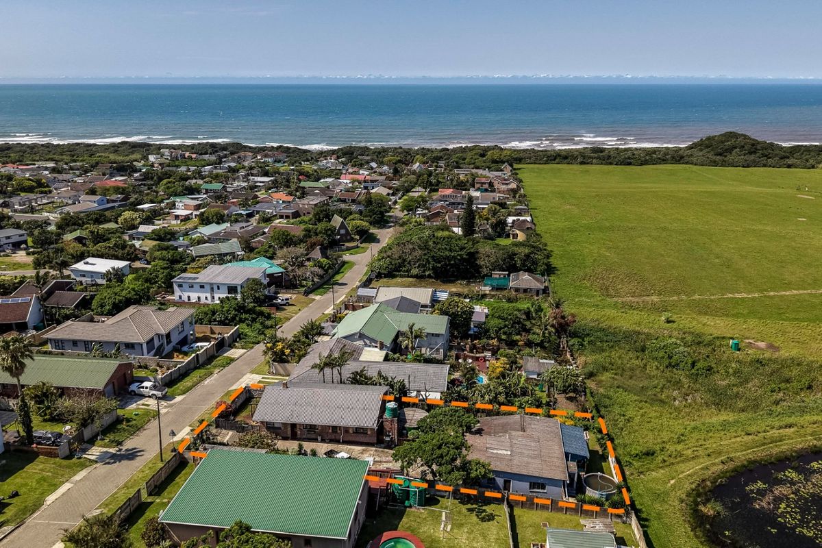 Aerial view of the property highlighting its location near the coastline, adjacent to open green space and a small pond.
