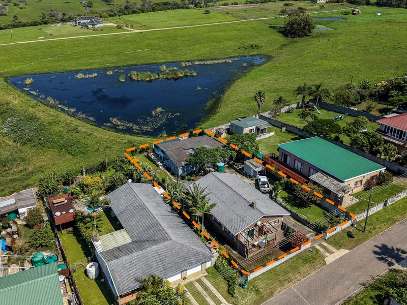 Aerial view of the property highlighting the residential plot, roof structures, and surrounding landscape with a nearby pond.