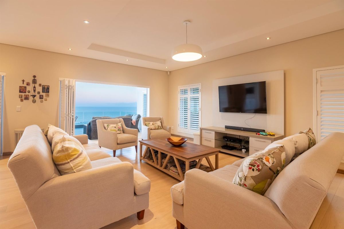 Spacious living room featuring recessed ceiling lighting, plantation shutters, and large sliding doors opening to a scenic ocean view.