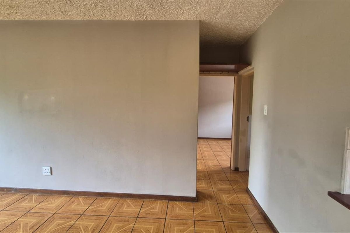 An empty living area featuring ceramic floor tiles, a textured ceiling, and a convenient pass-through window connecting to the adjacent space.