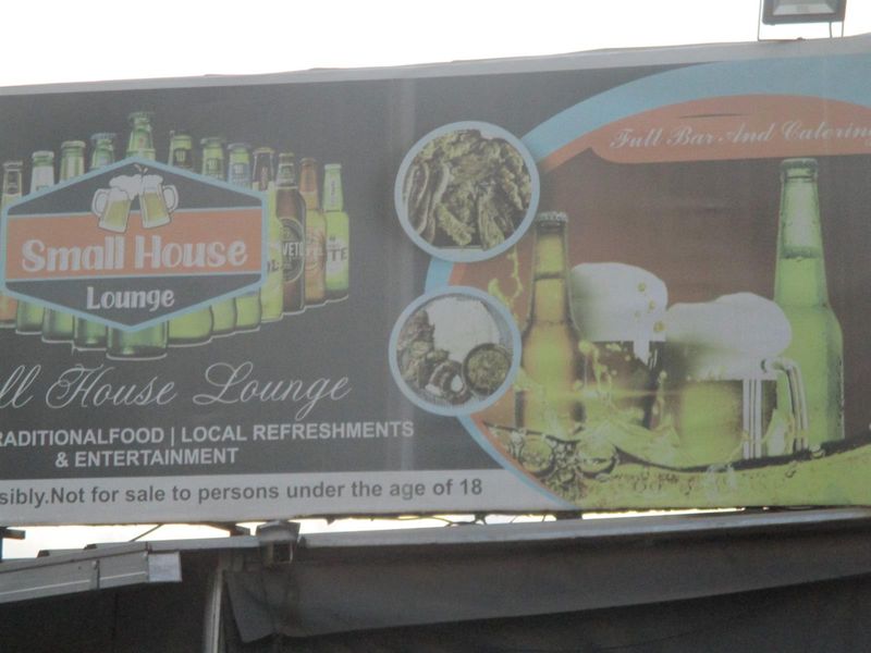 A large commercial signage board for Small House Lounge, displaying branding, food and beverage offerings, and entertainment information.
