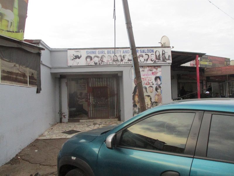 Front facade of a commercial salon property featuring a security gate entrance and exterior signage.