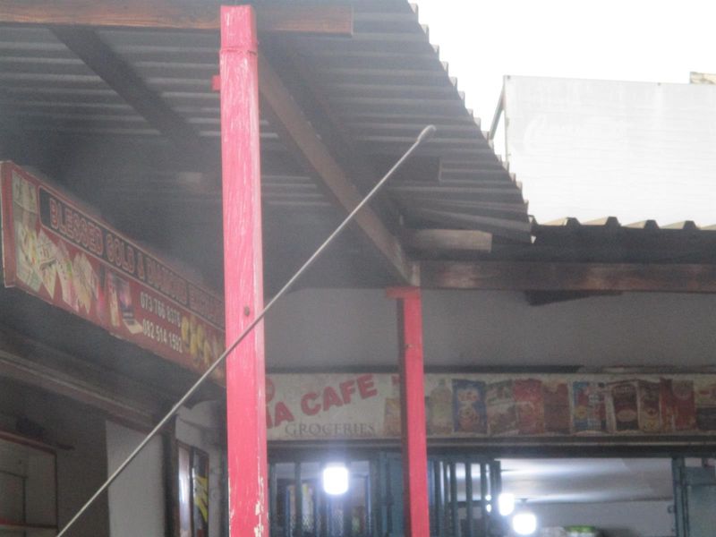 Front facade of a commercial storefront featuring a corrugated metal roof, painted support columns, and prominent business signage.