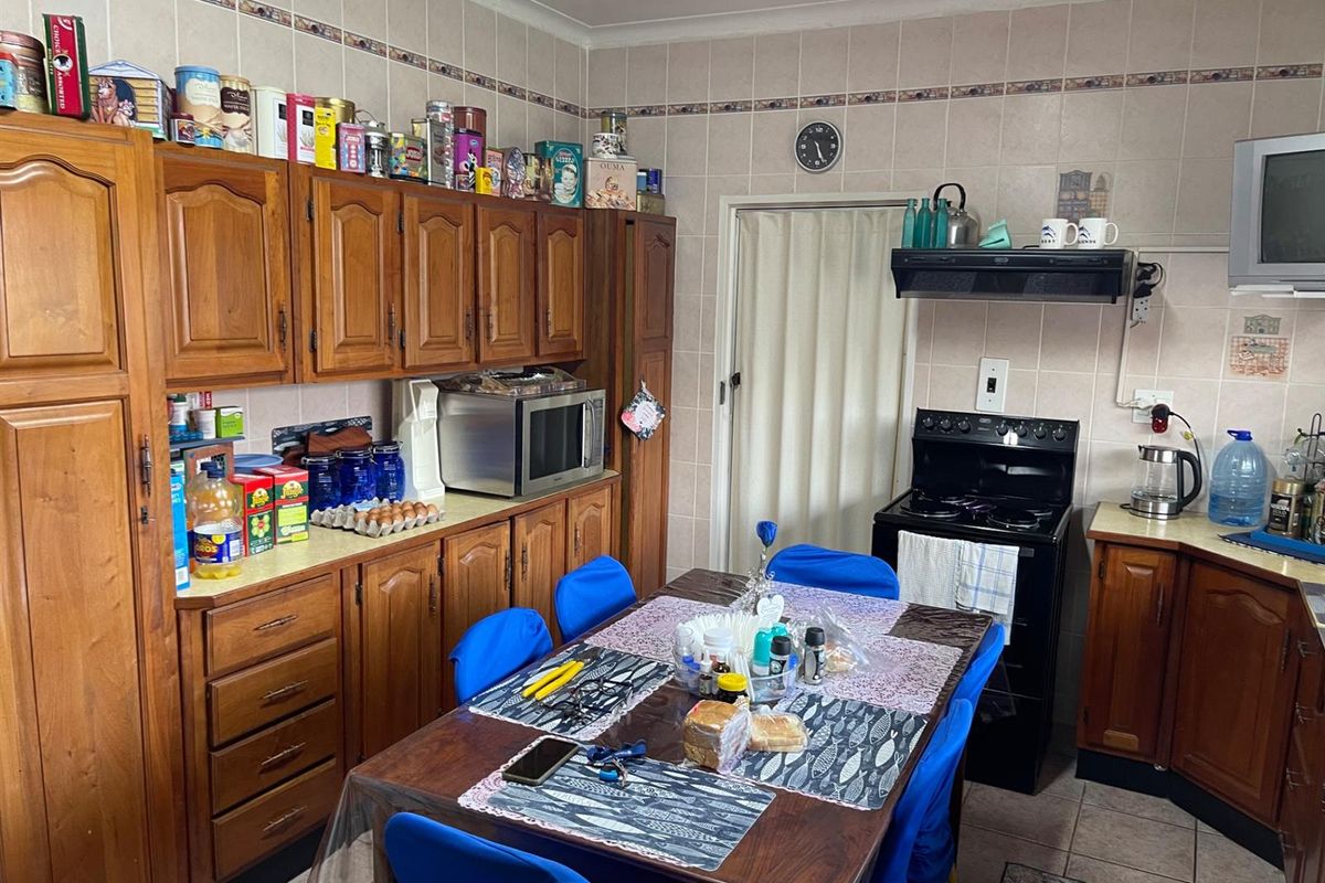 A functional kitchen featuring traditional timber cabinetry, tiled splashbacks, and a dedicated dining area, offering a classic layout with ample storage space.