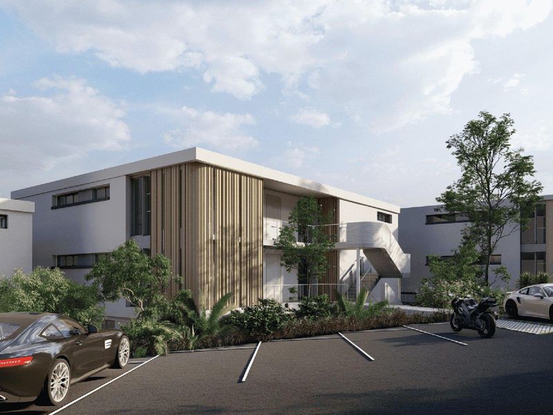 Modern apartment complex exterior featuring timber slat cladding, concrete staircases, and a paved parking area.