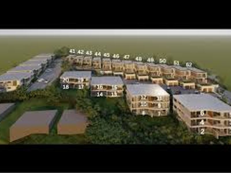An aerial perspective of a residential apartment complex development, showcasing the layout of multiple units and surrounding grounds.