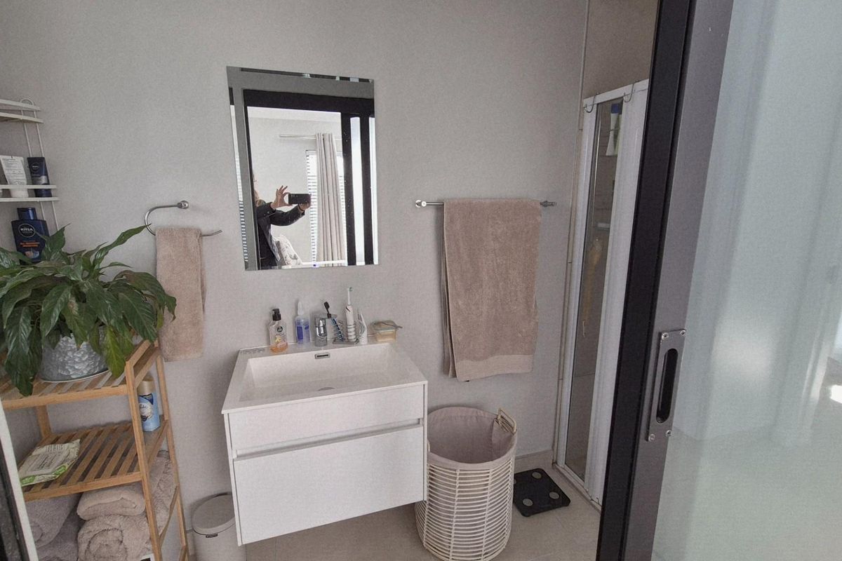 A modern bathroom featuring a wall-mounted vanity with an integrated basin, a wall mirror, and a separate shower enclosure with a sliding door.