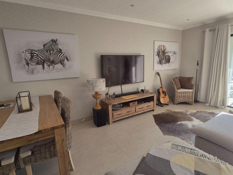 An open-plan living and dining area featuring neutral tiled flooring, recessed lighting, and a sliding glass door providing access to the outdoor space.