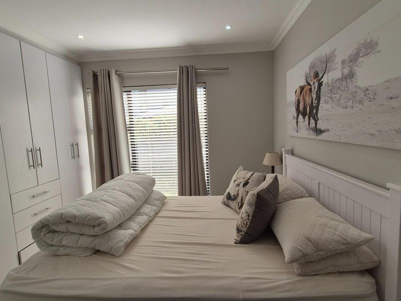 A well-maintained bedroom featuring ample built-in cupboard storage, recessed downlighting, and neutral finishes, creating a clean and functional living space.