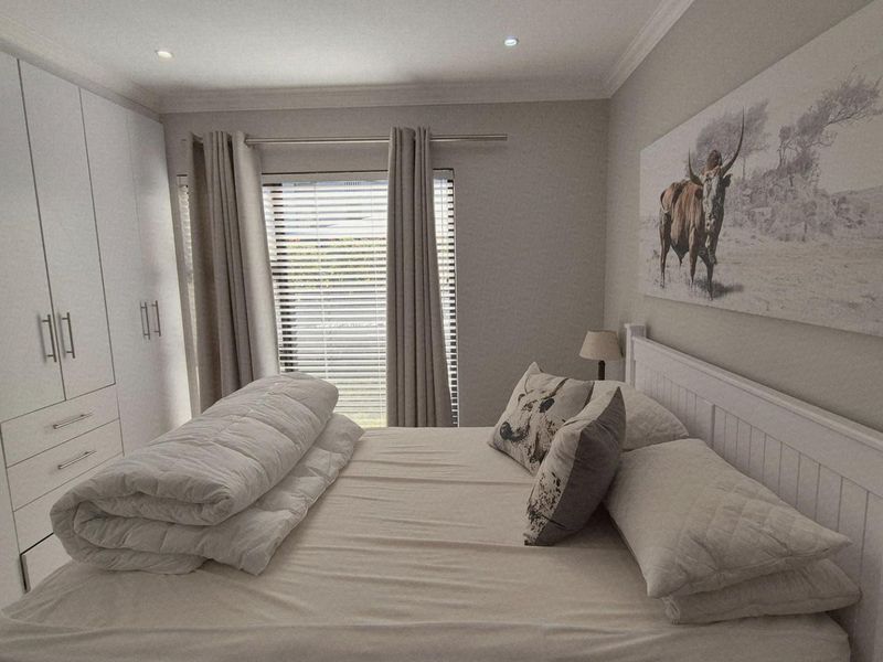 A well-maintained bedroom featuring ample built-in cupboard storage, recessed downlighting, and neutral finishes, creating a bright and comfortable living space.