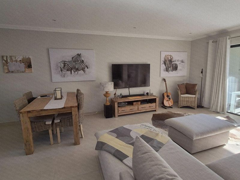 Spacious open-plan living and dining area featuring neutral tiled flooring, recessed lighting, and large sliding glass doors providing access to the patio.