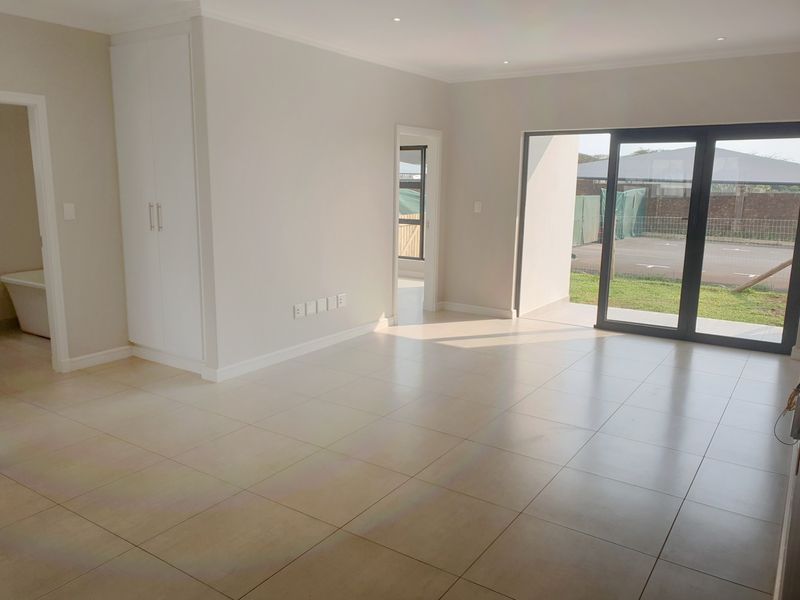 Spacious, light-filled living area featuring neutral tiled flooring, built-in storage, and large sliding glass doors providing seamless access to the outdoor space.