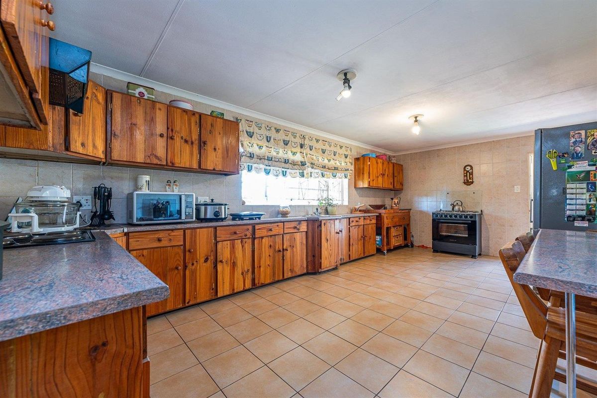 Spacious kitchen featuring solid wood cabinetry, tiled flooring, tiled splashbacks, and a built-in oven with hob.