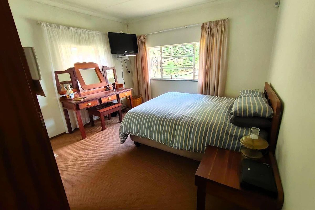 A functional bedroom featuring carpeted flooring, a window with security bars, and neutral wall finishes.