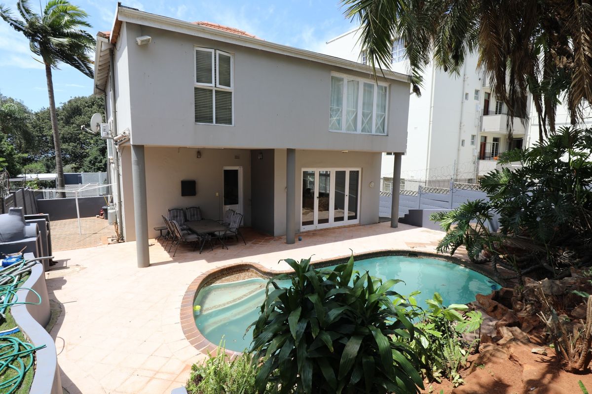Rear view of the property featuring a covered patio area, a swimming pool, and a paved outdoor space.
