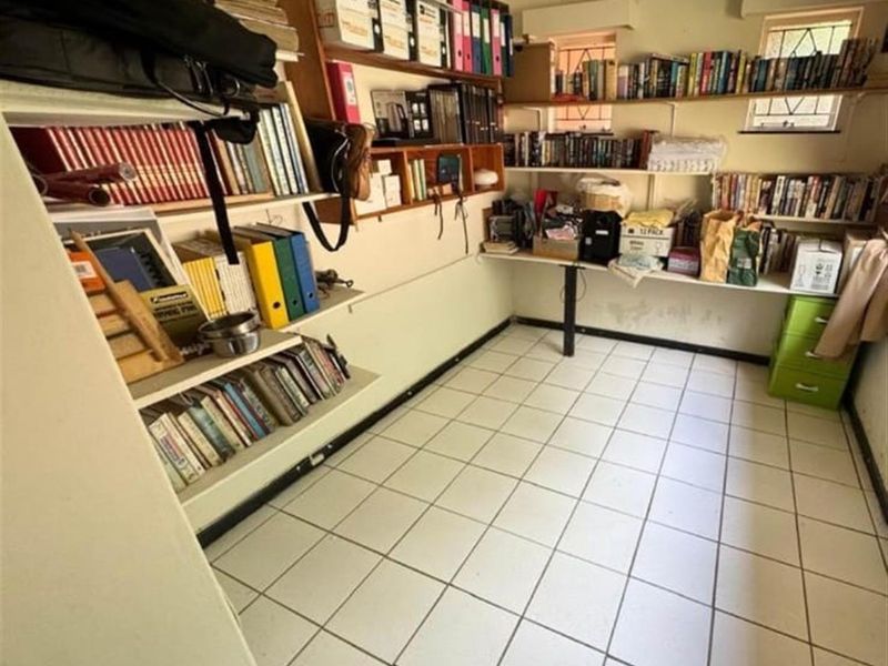 A functional utility room or home office space featuring tiled flooring and extensive built-in wall shelving units.