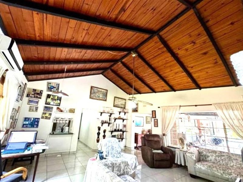 Spacious living area featuring a high vaulted timber-clad ceiling with exposed beams, tiled flooring, and a wall-mounted air conditioning unit.