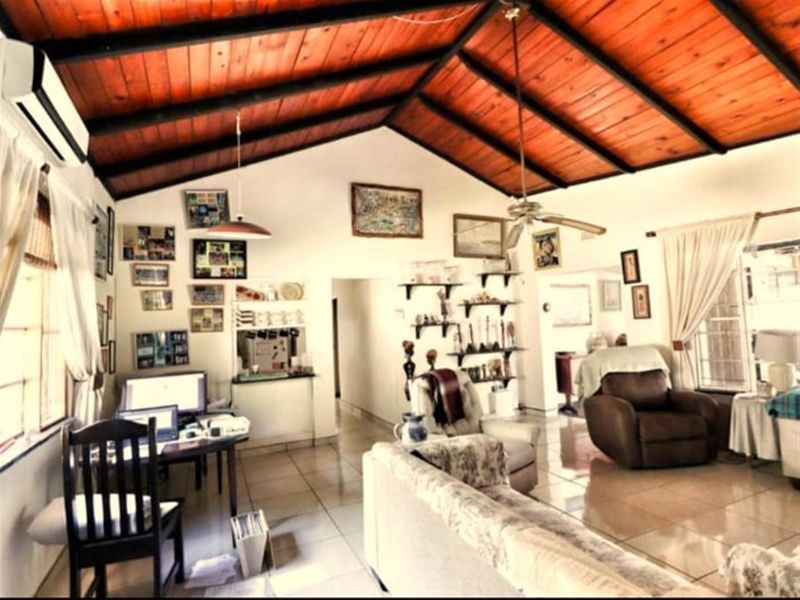 Spacious open-plan living area featuring a high vaulted timber-clad ceiling, tiled flooring, and a wall-mounted air conditioning unit.
