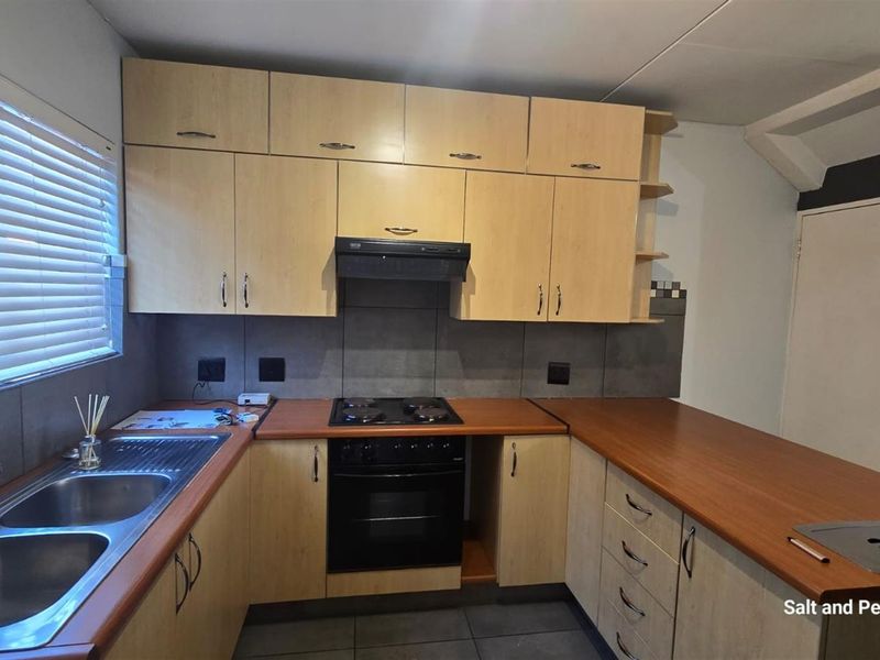 Functional kitchen featuring light wood cabinetry, dark countertops, a built-in oven with extractor fan, and a double stainless steel sink.