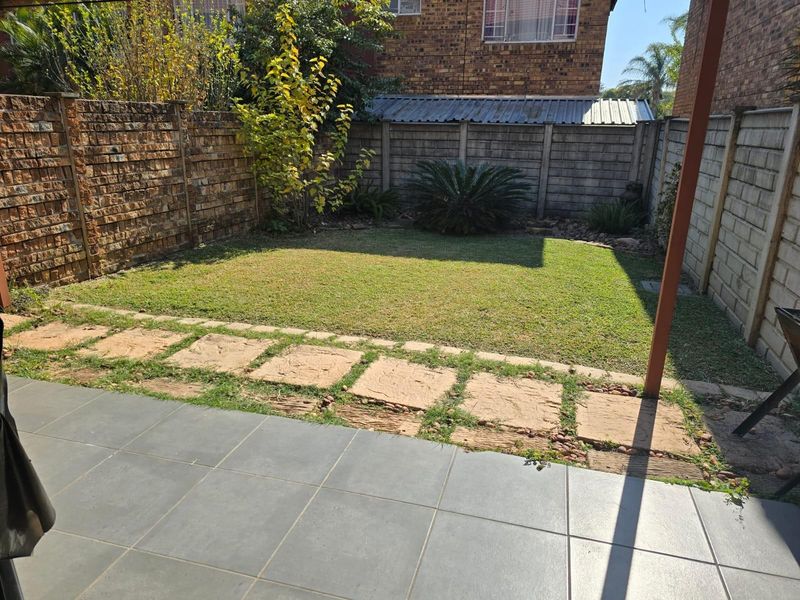 A private rear garden featuring a tiled patio area, a small lawn, and secure perimeter walling.
