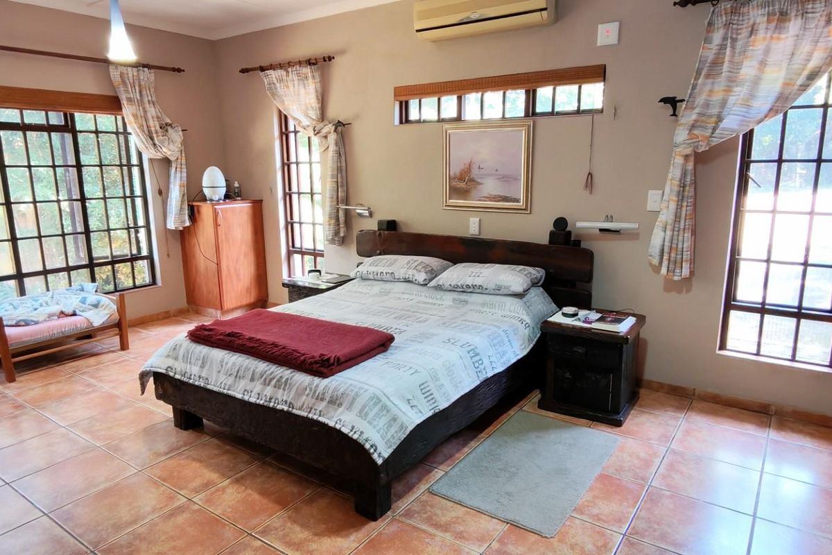 Spacious bedroom featuring tiled flooring, large windows providing natural light, and a wall-mounted air conditioning unit.