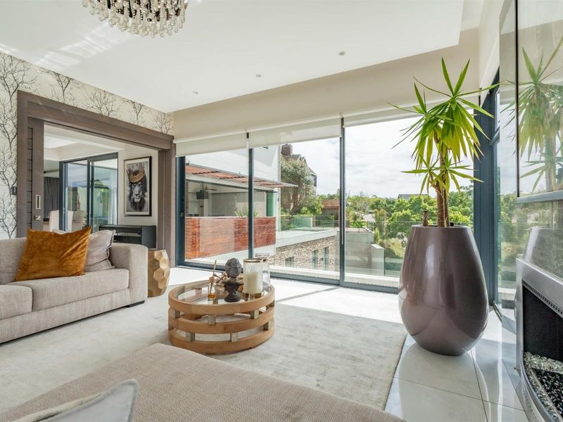 Modern living room featuring large sliding glass doors, built-in fireplace, recessed lighting, and elegant tiled flooring with views of the surrounding area.