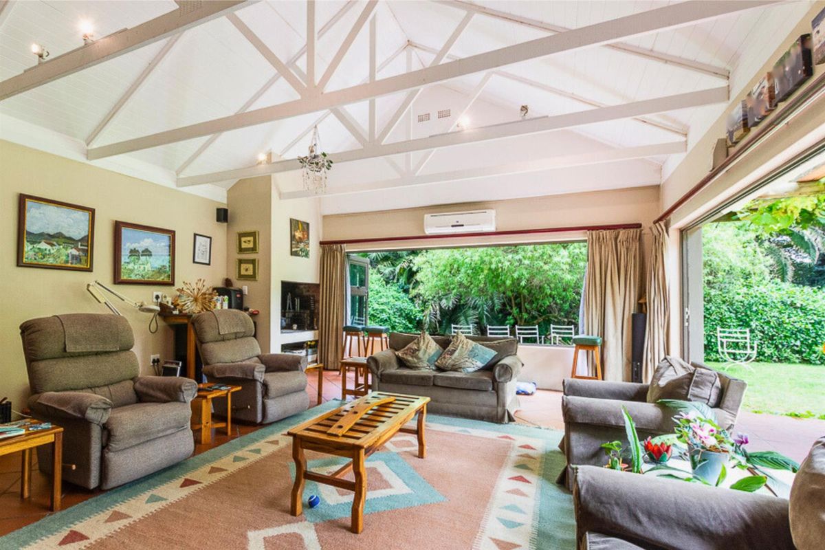 Spacious living room featuring high vaulted ceilings with exposed trusses and large sliding doors opening onto a covered patio and garden.