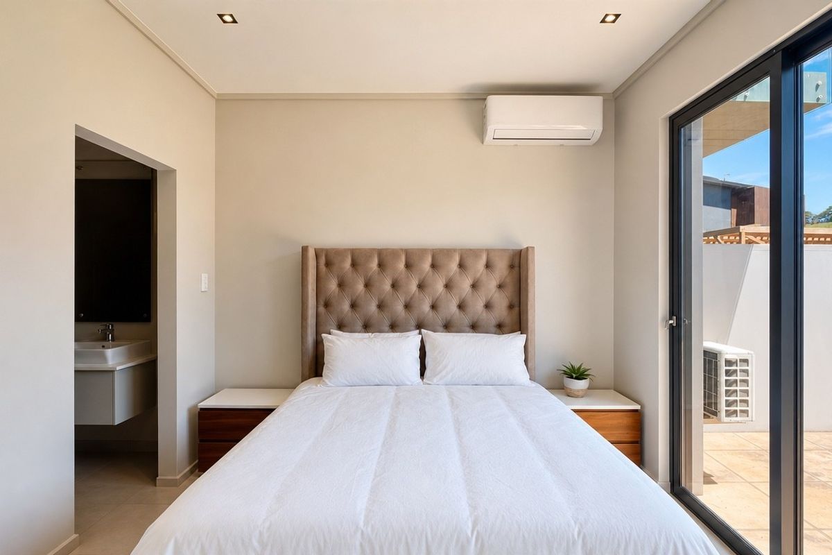 A modern, well-maintained bedroom featuring recessed lighting, an integrated air conditioning unit, and direct access to an outdoor patio through sliding glass doors.