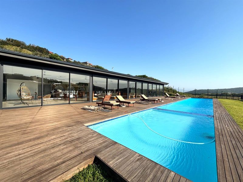 Spacious outdoor pool area featuring extensive timber decking and large sliding glass doors providing seamless indoor-outdoor flow.