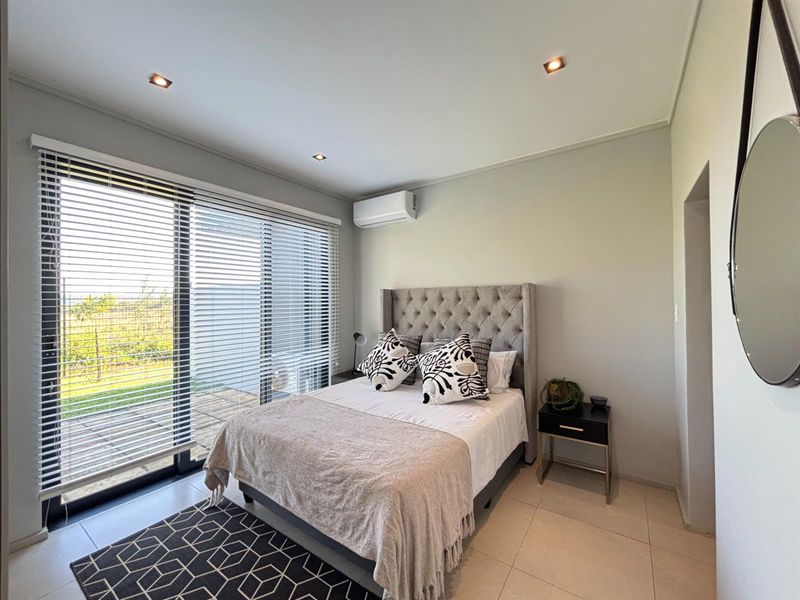 A well-maintained bedroom featuring tiled flooring, recessed lighting, a split-system air conditioner, and large sliding glass doors with venetian blinds providing outdoor access.