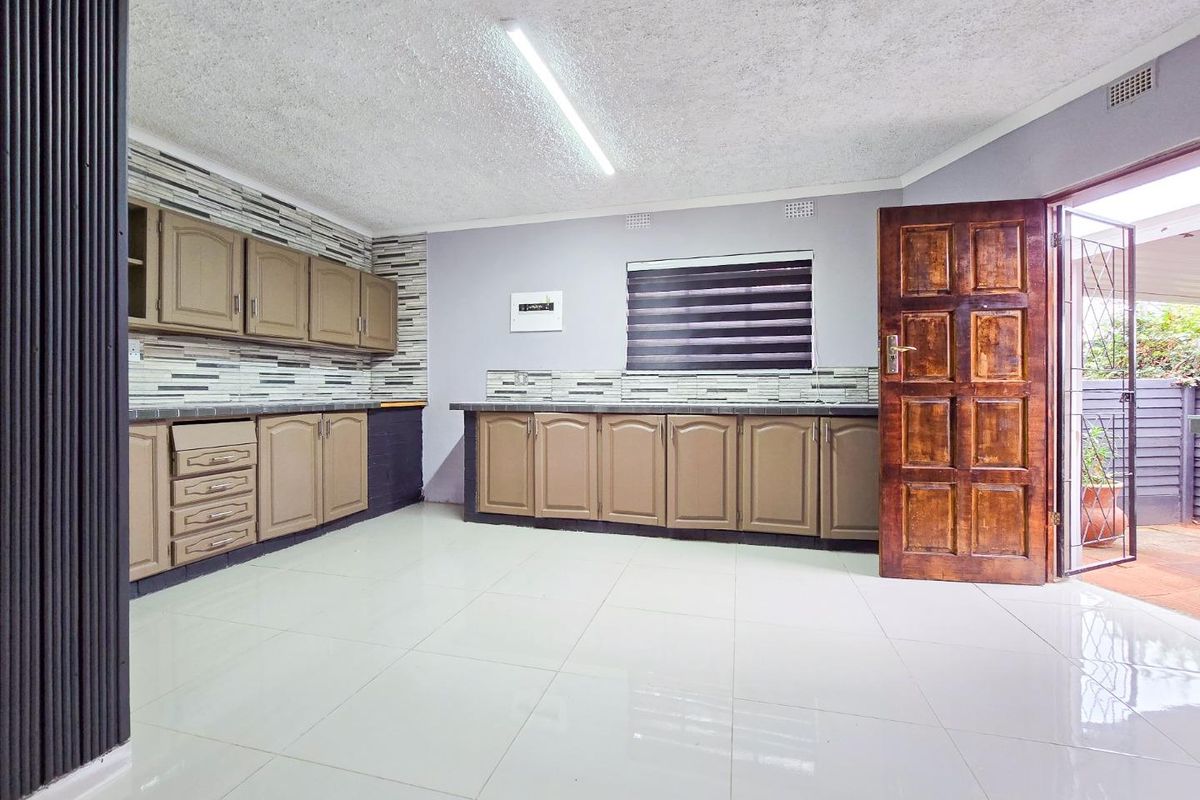 Spacious kitchen featuring built-in cabinetry, tiled flooring, and a tiled backsplash, with direct access to an outdoor patio area.