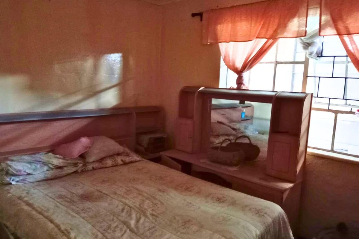 A bedroom featuring a built-in headboard and vanity unit, with a window providing natural light.