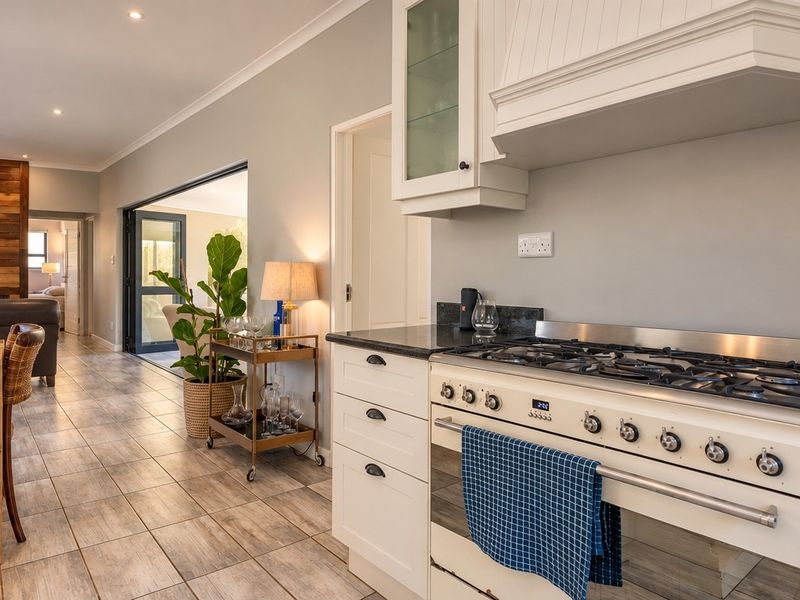 Spacious open-plan kitchen and living area featuring a gas stove, stone countertops, and seamless flow to the outdoor patio through large sliding glass doors.
