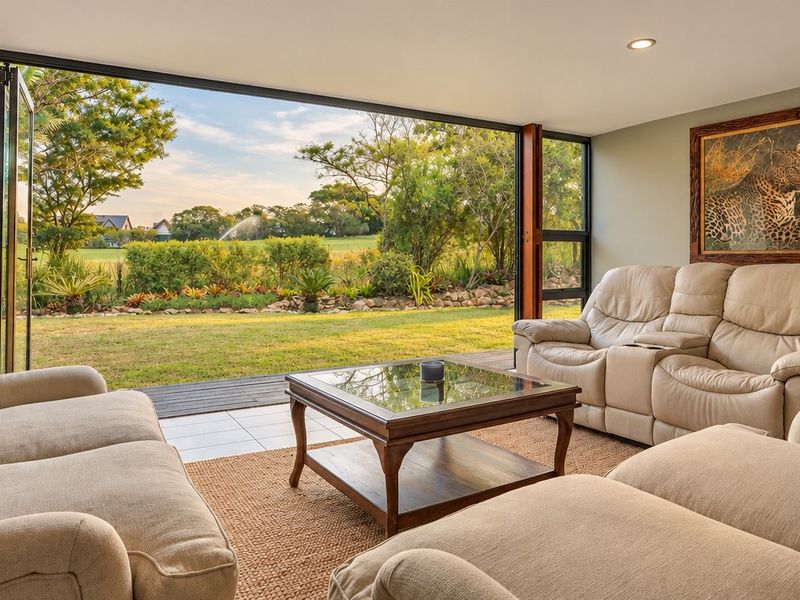 Spacious living room featuring large bi-fold doors that open onto a landscaped garden, providing seamless indoor-outdoor flow and natural light.