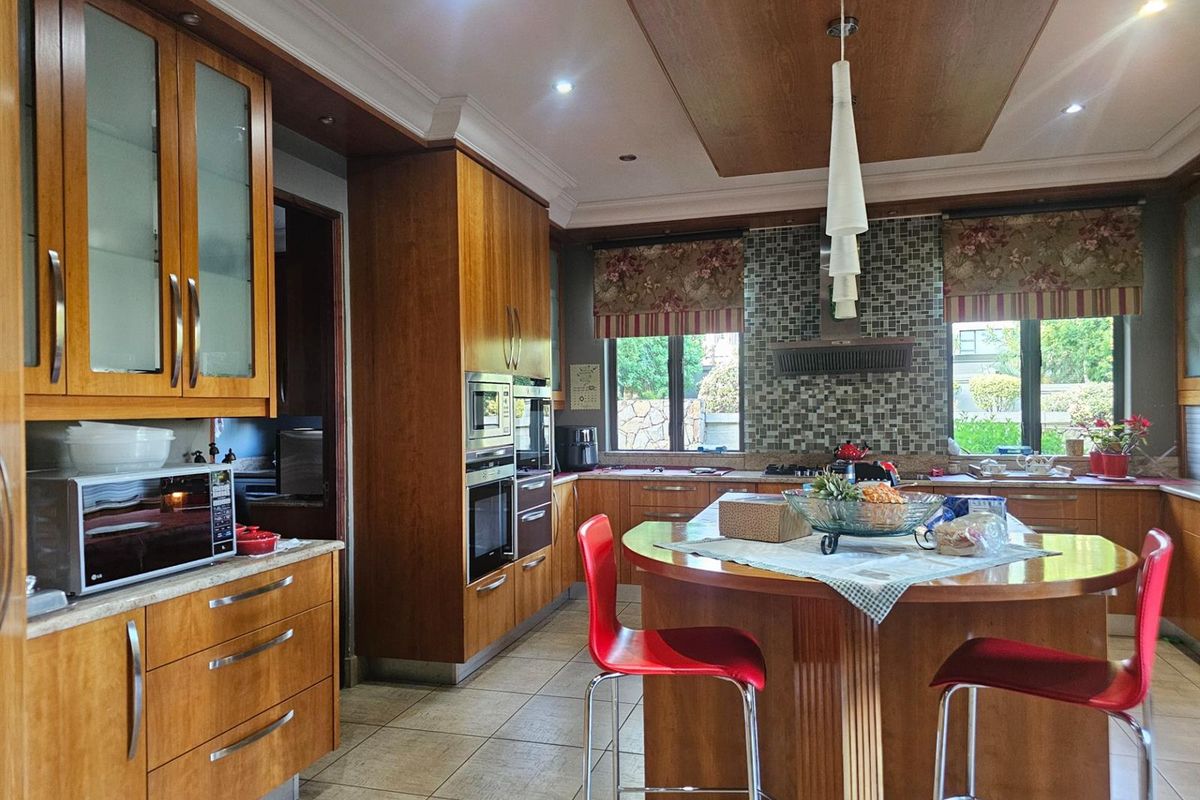 Spacious kitchen featuring warm wood cabinetry, a central island with breakfast bar seating, built-in oven, and mosaic tile backsplash.