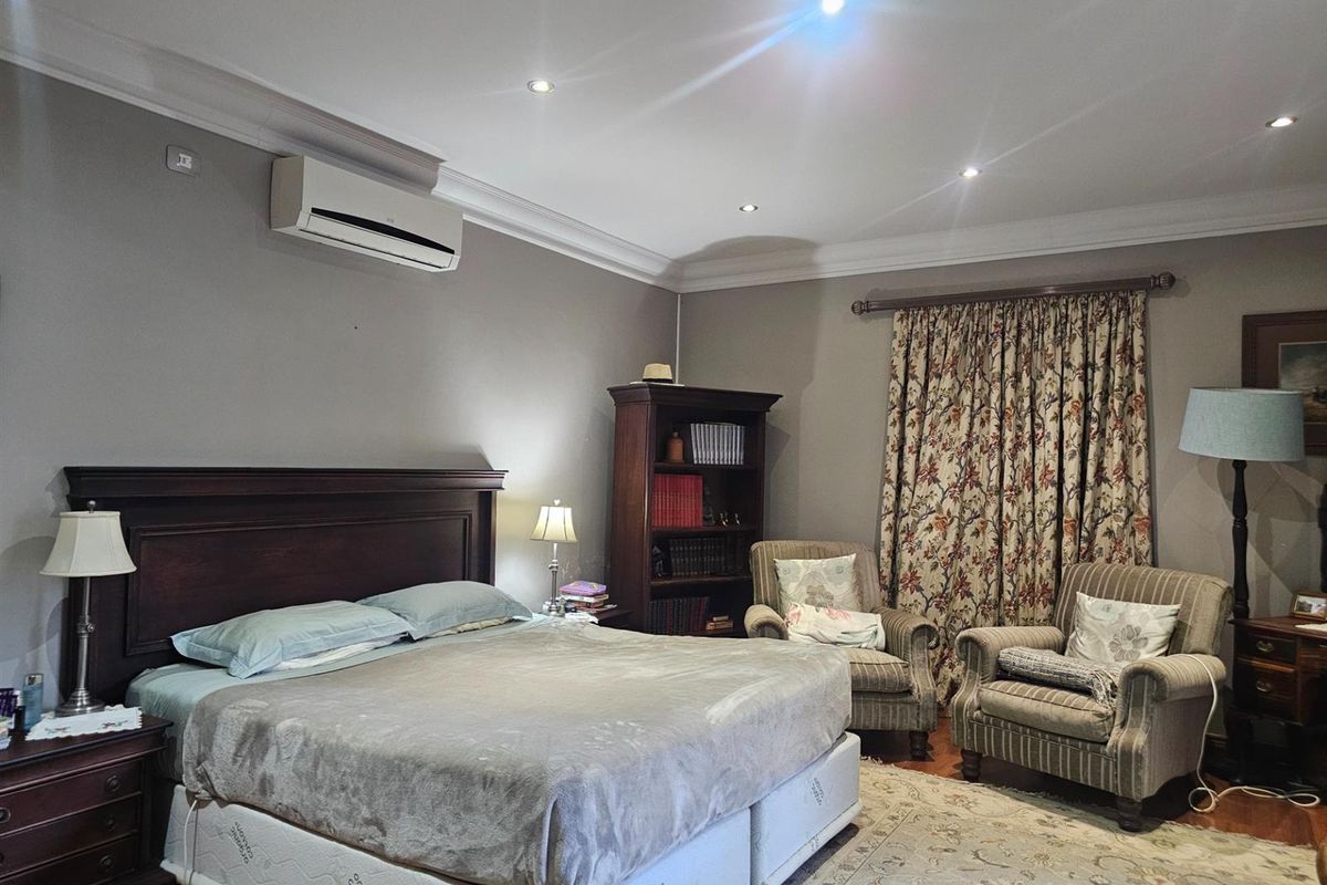 Spacious bedroom featuring hardwood flooring, crown molding, recessed lighting, and a wall-mounted air conditioning unit.