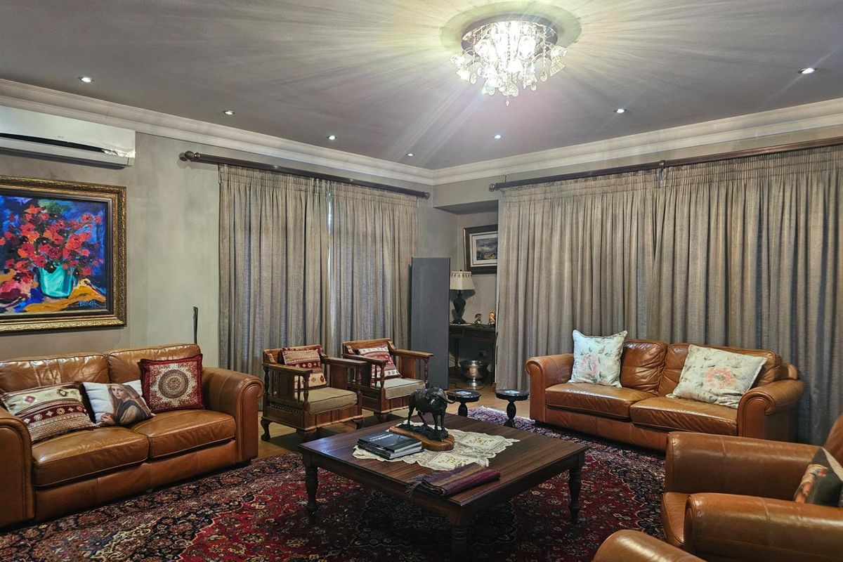Spacious living room featuring recessed downlighting, decorative crown molding, and a wall-mounted air conditioning unit, creating a comfortable and well-defined lounge area.