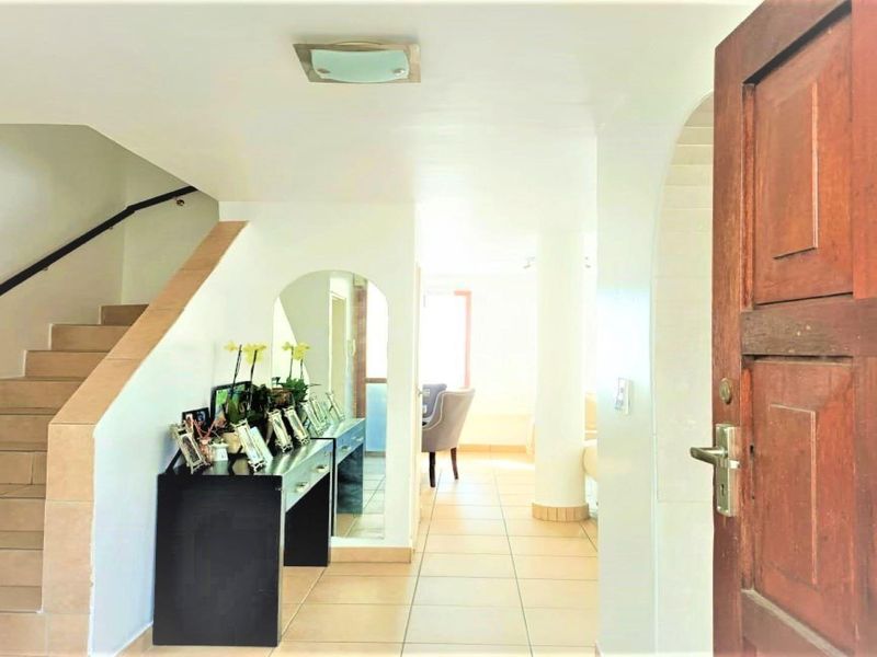 Welcoming entrance hall featuring tiled flooring, a staircase leading to the upper level, and an open-plan layout connecting to the main living area.