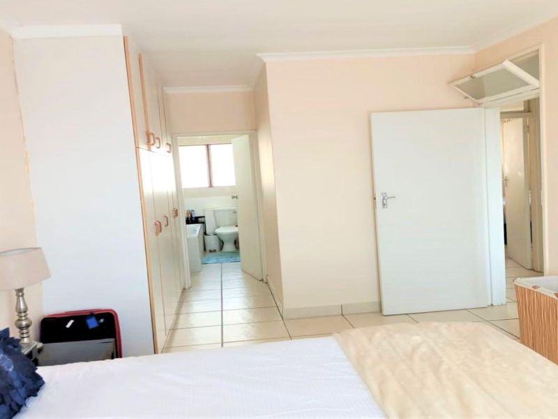 Bedroom featuring built-in cupboards, tiled flooring, and direct access to an en-suite bathroom.