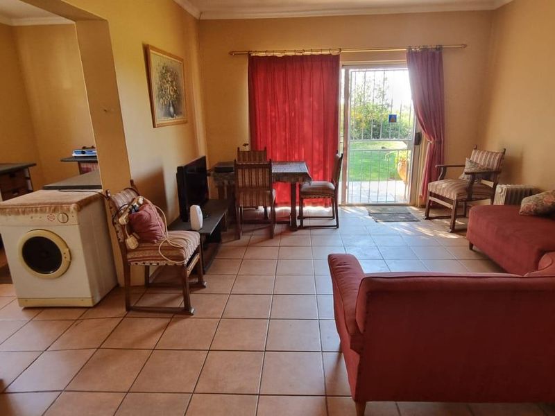 Open plan living area featuring tiled flooring, a compact kitchen corner, and direct access to the garden through a sliding glass door.