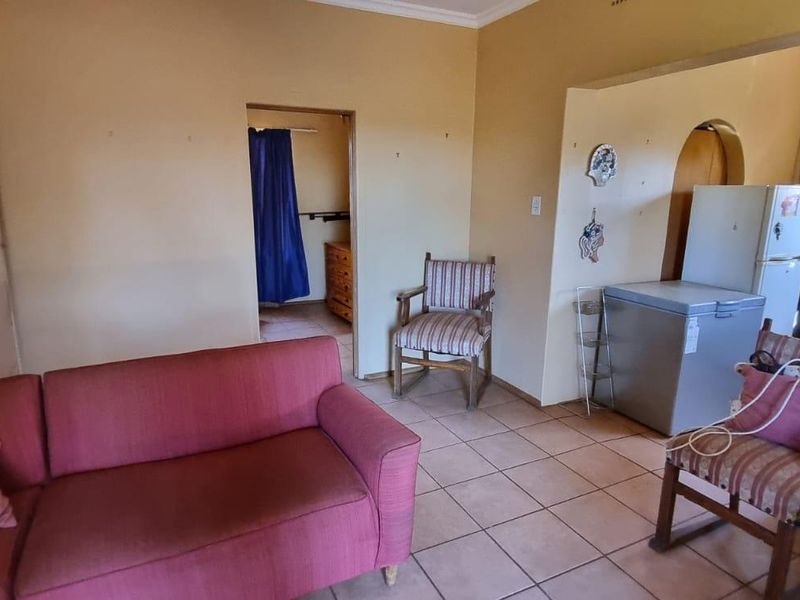 An open-plan living area featuring tiled flooring and direct access to adjacent rooms, offering a functional layout with potential for modernization.